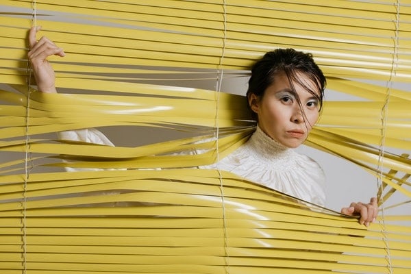 woman wedged between the slats of a blind