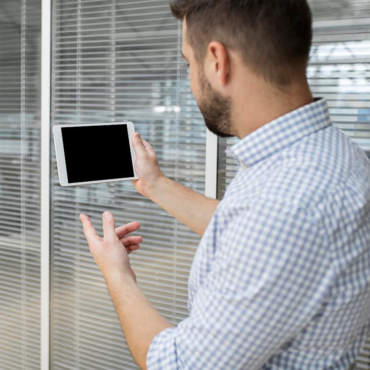 Hombre controlando persiana domotizada con tablet