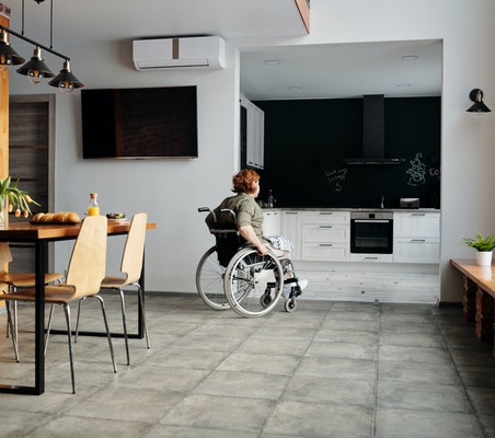 persona en silla de ruedas dirigiéndose a la cocina de una casa domótica