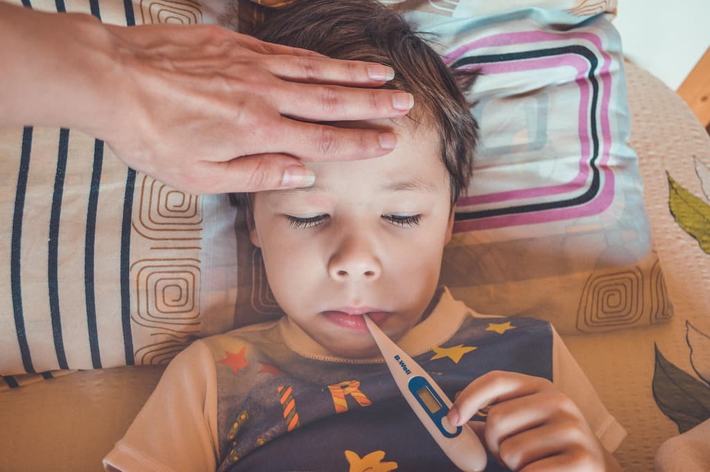 child with fever with a thermometer