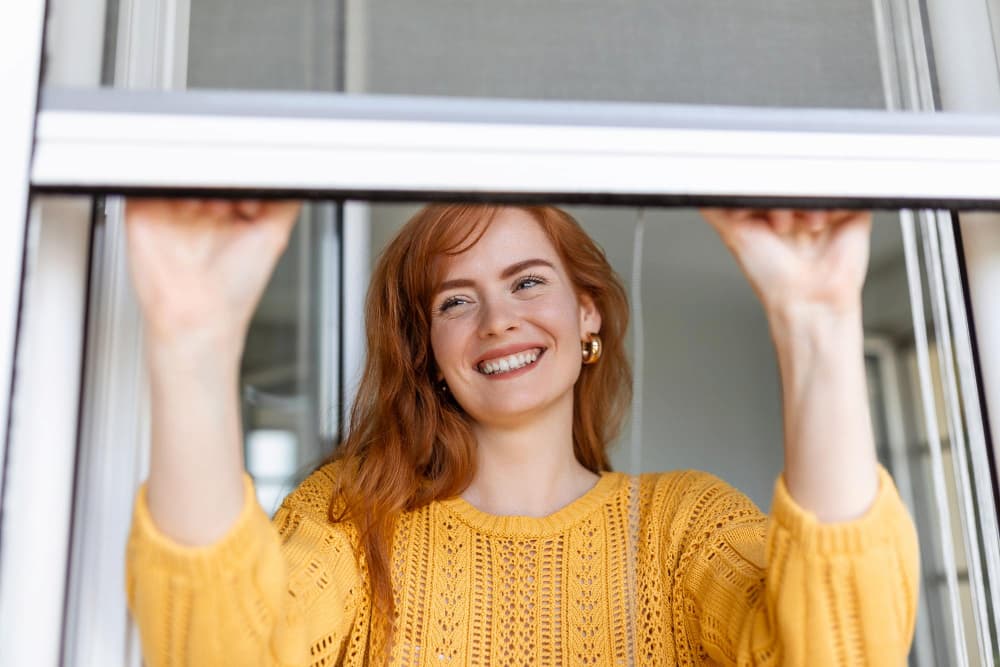 Mujer cerrando ventana con mosquitera